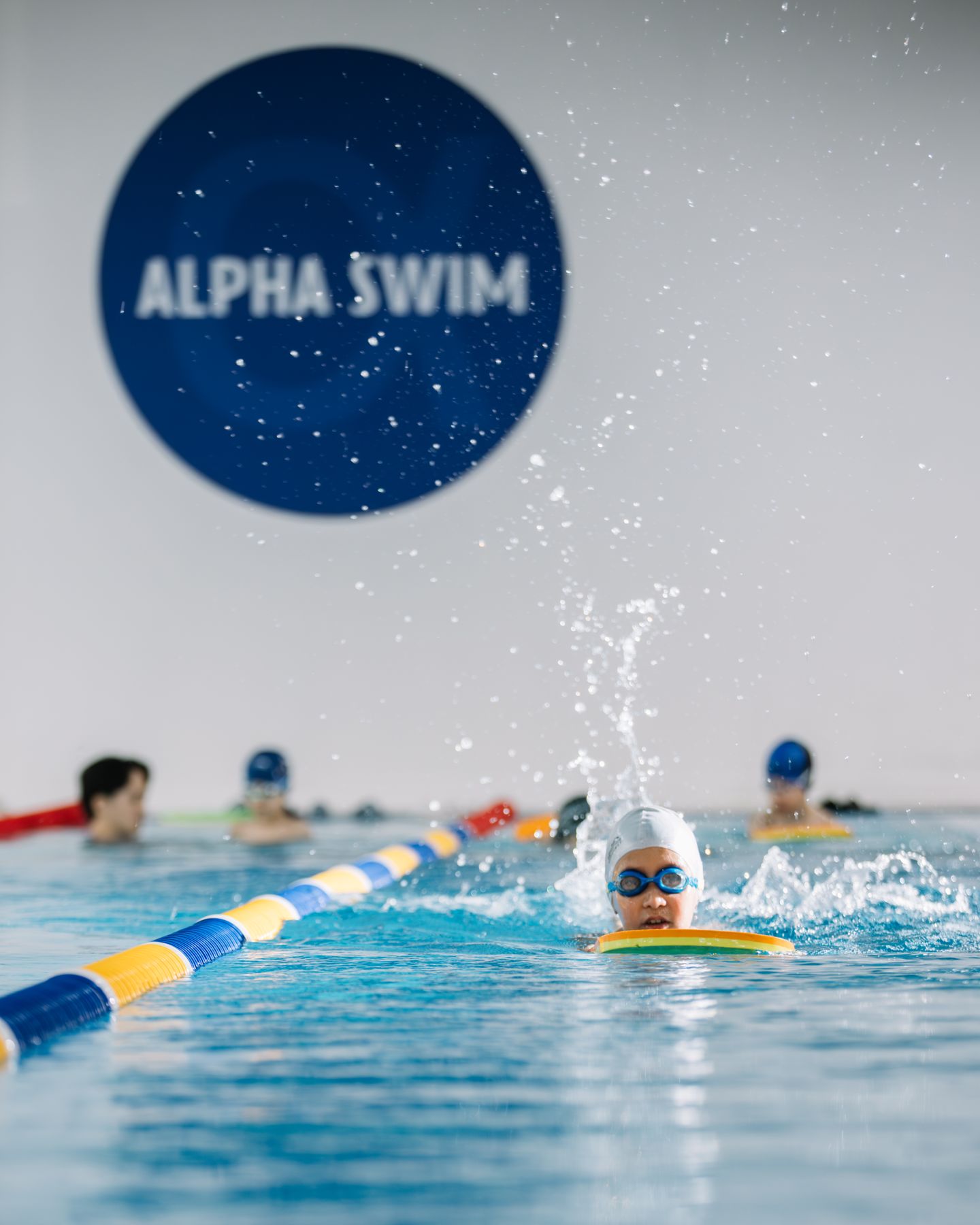 Ребёнок плывёт на фоне логотипа Alpha Swim
