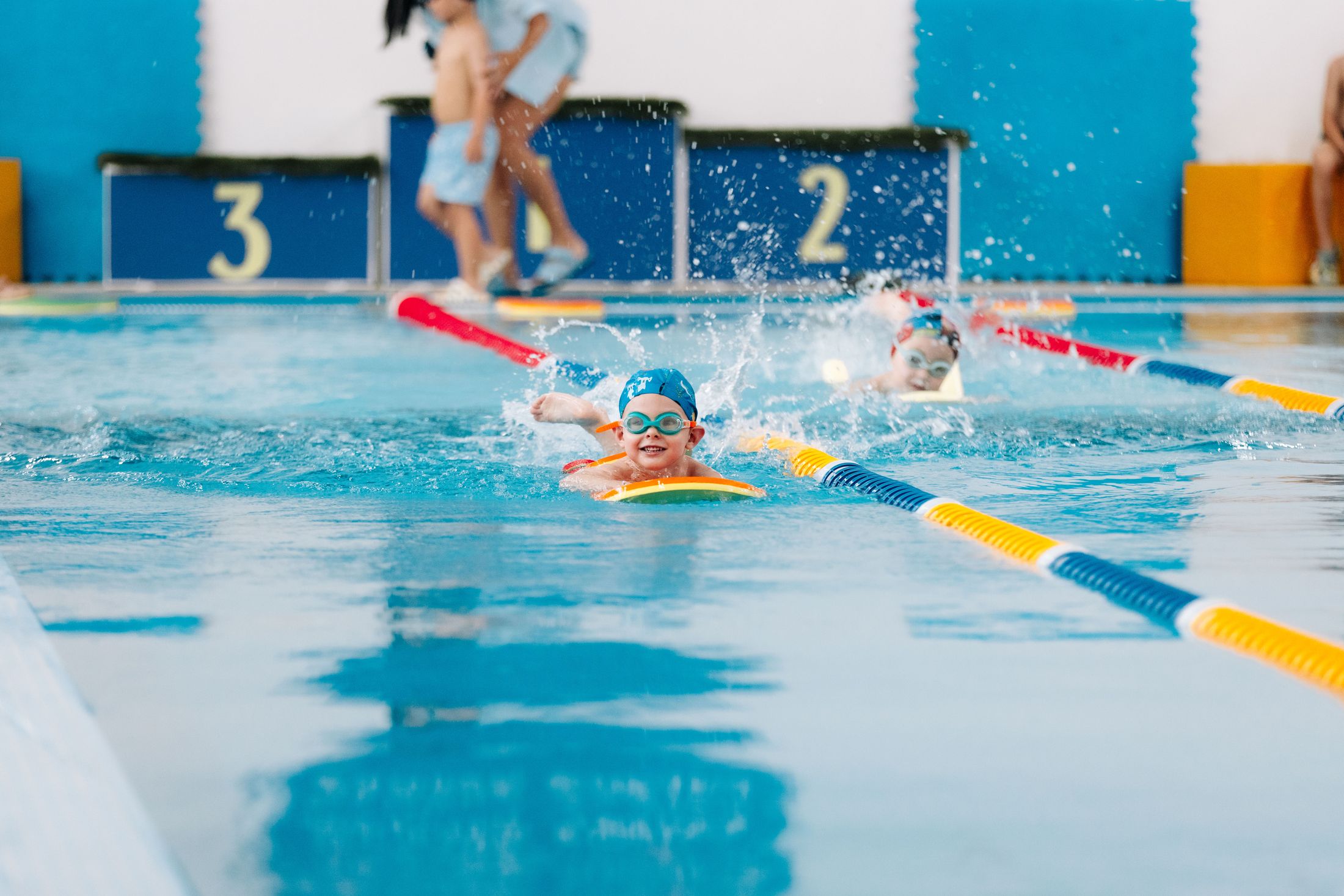 Ребёнок плывёт с доской по дорожке бассейна Alpha Swim